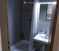 Modern bathroom with a bathtub, toilet, sink, and shower area with a curtain. Features a mirror with built-in lighting and a window allowing natural light.