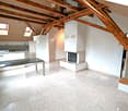 Open-plan living and dining area with exposed wooden beams, a modern kitchen, a fireplace, and a dining table.