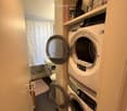 Bathroom with a washing machine and dryer unit, toilet, sink, and shower area with a curtain.