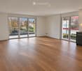 Empty room with wooden flooring, large glass sliding doors, and white walls.