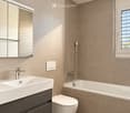 Modern bathroom with beige tiled walls, a white sink with a chrome faucet, a large mirror, a bathtub with a handheld showerhead, and a toilet. The floor is dark tiled.