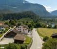 A scenic view of a village nestled in a valley with houses, a road, and surrounding mountains.
