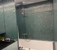 Modern bathroom with a bathtub, showerhead, sink, and various toiletries on the counter.