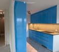 Modern kitchen with blue cabinets, white countertops, and a sink. The space is clean and well-lit with recessed lighting.