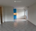 Empty room with tiled floor, white walls, and a small blue cabinet visible in the background.
