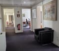 Office hallway with a black leather chair, desk, office chair, and framed artwork on the walls.