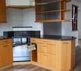 Modern kitchen with wooden cabinets, black granite countertops, and stainless steel appliances including an oven and dishwasher.