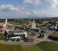 Aerial view of an industrial and residential area with multiple buildings, parking lots, and surrounding green fields.