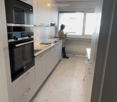 Modern kitchen with white cabinets, a built-in oven, and a sleek countertop, illuminated by a round ceiling light.