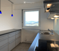 Modern kitchen with stainless steel sink, faucet, stove, and grey cabinets. Large window offers a scenic view.