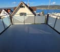 Balcony with modern glass balustrade, overlooking a scenic lake and town view.