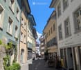 urban street, multi-story buildings, brick walls, balconies, street with parked bicycles, clear sky