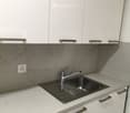 Modern kitchen with white cabinets, marble backsplash, and stainless steel sink.