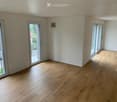 Empty room with wooden flooring, large sliding glass doors, and white walls.