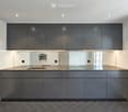 Modern kitchen with dark grey cabinets, stainless steel sink, and built-in oven.