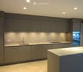 Modern kitchen with grey cabinets, a central island, and a sink with a faucet. The space features recessed lighting and a sleek design.