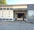 Two-story industrial building with a large garage entrance, circular windows, and a covered walkway.