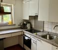 Modern kitchen with white cabinets, granite countertops, stainless steel sink, and built-in appliances including an oven and stove.