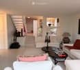 Modern living room with white walls, light wood flooring, and contemporary furniture including a white sofa, ottoman, coffee table, and decorative items.