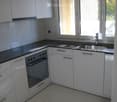 Modern kitchen with white cabinets, stainless steel sink, and built-in oven. Features a black countertop and tiled backsplash.