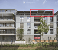 Modern multi-story residential building with balconies, large windows, and contemporary design. Features include a rooftop terrace with outdoor seating and a fenced garden area at the base.