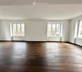 Empty room with wooden flooring and large windows, no furniture or equipment present.