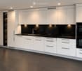 Modern kitchen with white cabinets, black countertops, and built-in appliances including an oven and sink.
