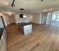 Empty room with wooden flooring, white walls, and large glass sliding doors leading to a balcony area.