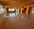 Empty room with polished concrete floor, wooden ceiling, and large windows. Bare walls and no furniture.