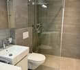 Modern bathroom with a white sink, toilet, glass-enclosed shower, and a towel on the counter.