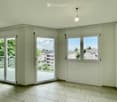 Empty room with tiled floor, large windows, and sliding glass doors leading to a balcony.
