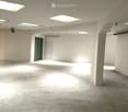 Empty underground parking space with concrete floors and walls, featuring a single green door and several square ceiling lights.