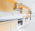 Modern kitchen with white cabinets, granite countertops, built-in oven and stove, dishwasher, and washing machine