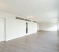 Empty room with white walls, wooden floor, and ceiling lights