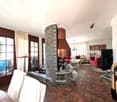 Living room, white walls, fireplace, brick column, tile flooring, sofa, coffee table, curtains, chandelier, artwork, jukebox, table, chairs
