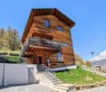 2-story wooden cabin with a slanted roof, balcony, and stairs leading up to the entrance.