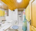 white tiled walls, shower, toilet, sink, mirror, yellow towels