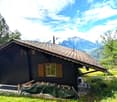 Log cabin style house, brown shingles, wooden windows, exterior grill, mountainous area, greenery surrounding