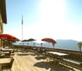 balcony with tables and chairs, red Coca Cola umbrellas, a flag, and scenic view of mountains