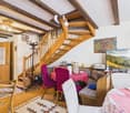 Dining area with wooden staircase, dining table, chairs, TV, rug, and decorative items