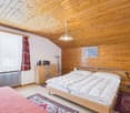 bedroom with wooden walls, bed, nightstands, cabinet, radiator, rug, lamp, books