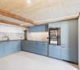 modern kitchen with gray cabinets, white tiled floor, wooden ceiling, sink, oven, dishwasher, washing machine