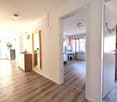 Empty room with wooden floor, white walls, wooden cabinet, mirror, and a window with curtains