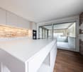 modern kitchen with white countertops, white cabinets, open to balcony with sliding glass door