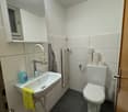 white walls, sink with faucet, radiator, toilet, tissue, trash can