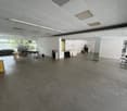 empty room, high ceiling, grey flooring, office desks, chairs, cabinets, window