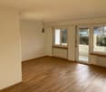 Empty room with wooden floor, white walls, radiators, sliding doors to a balcony