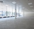 Empty room with white ceiling, concrete floor, glass windows, and metal pillars