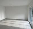 Large open space with white walls, tile flooring, and a sliding glass door leading to an exterior area.