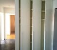 Four open white wardrobes with sliding doors in an empty room